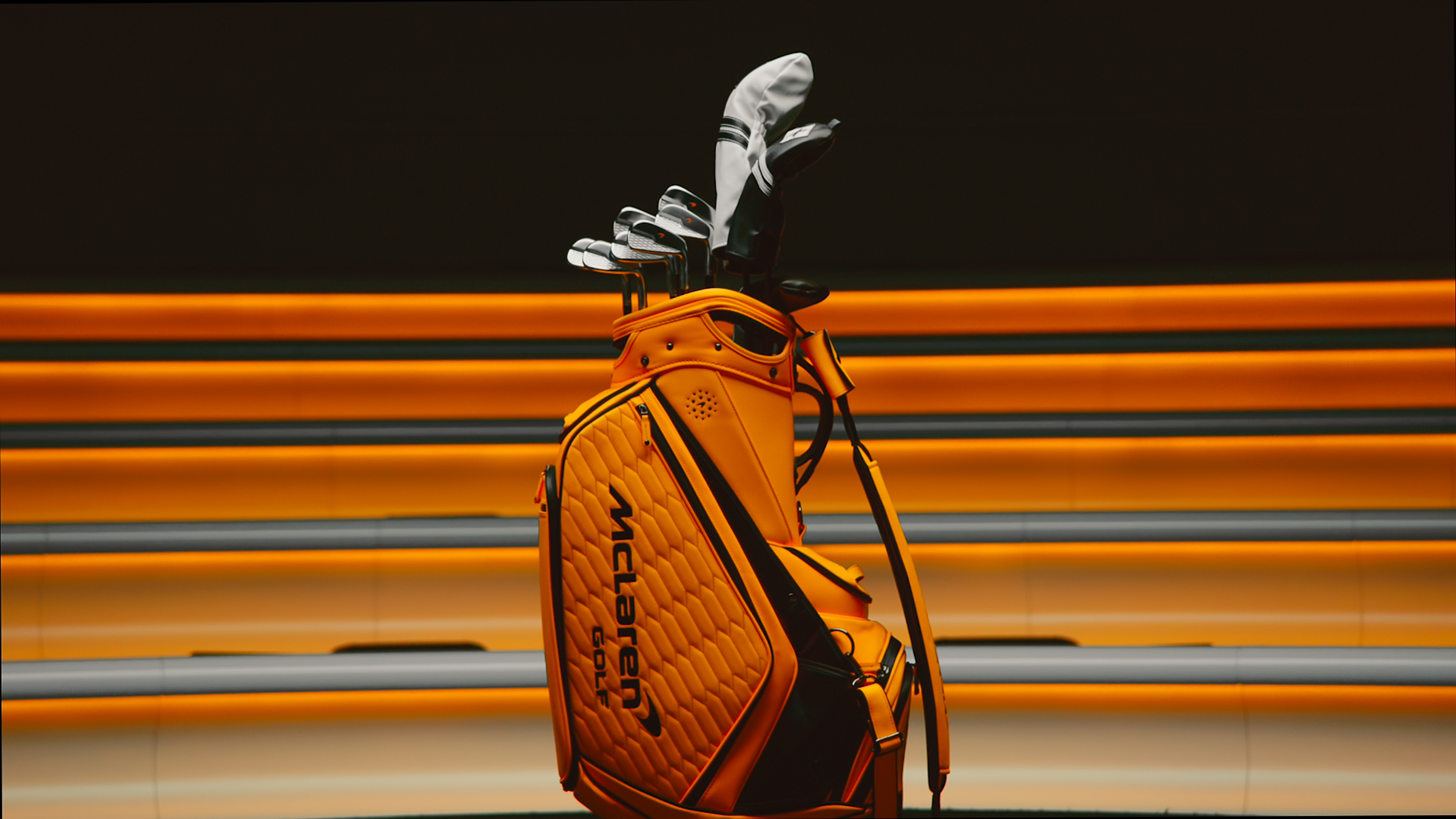 Bright orange McLaren Golf bag holding a selection of golf clubs